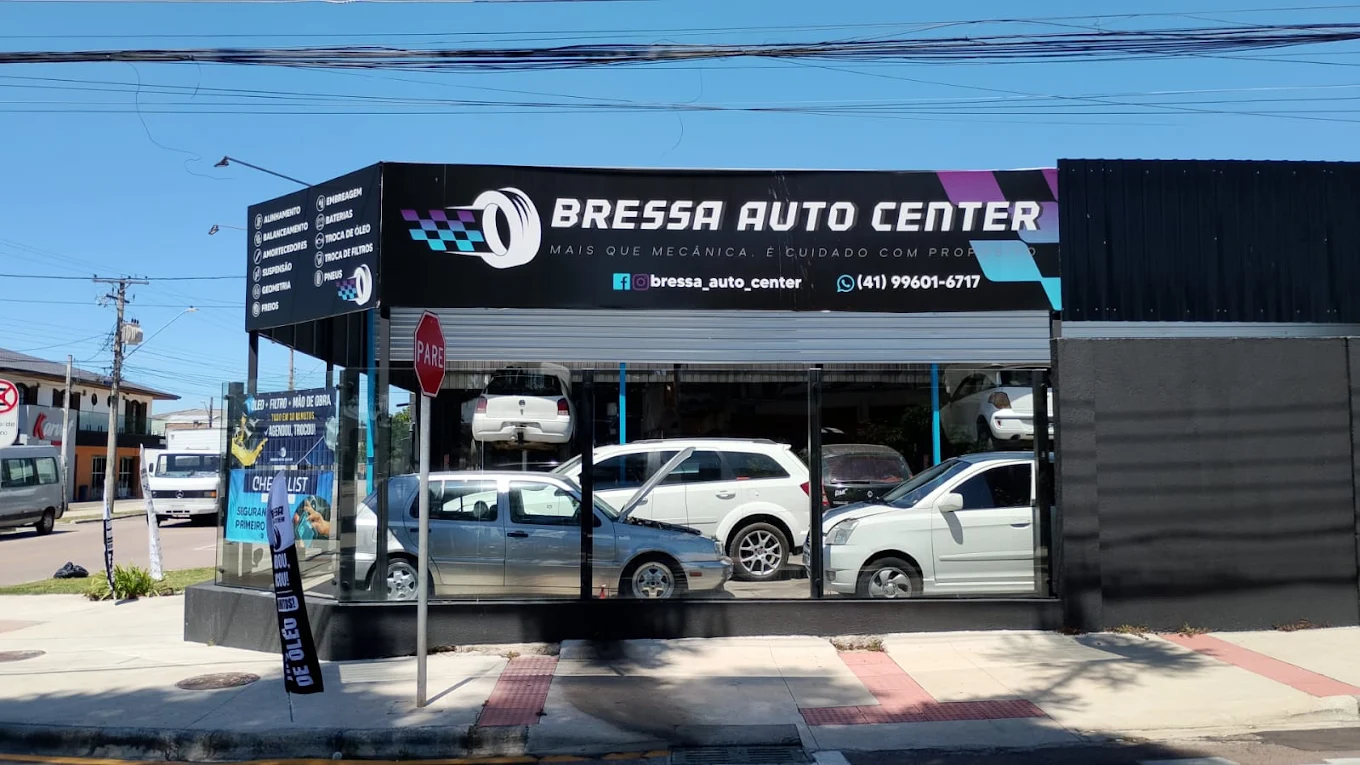 Fachada da loja Bressa Auto Center, com fachada preta, letreiro iluminado e carros na oficina